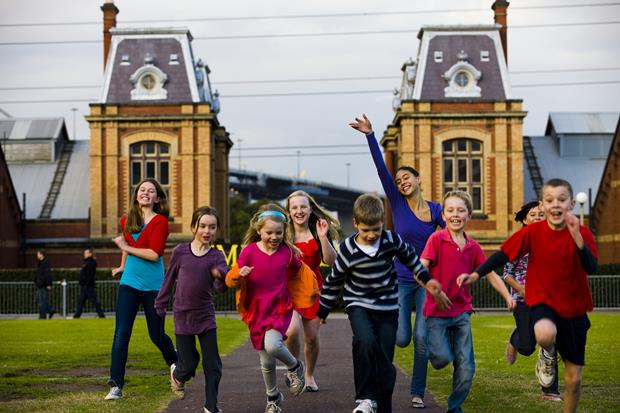 Group of children running towards the camera. Old brick building in the background