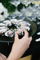 Hand lifting an oyster from a plate
