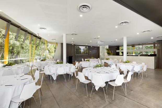 Room set up with round tables and chairs with white tablecloths